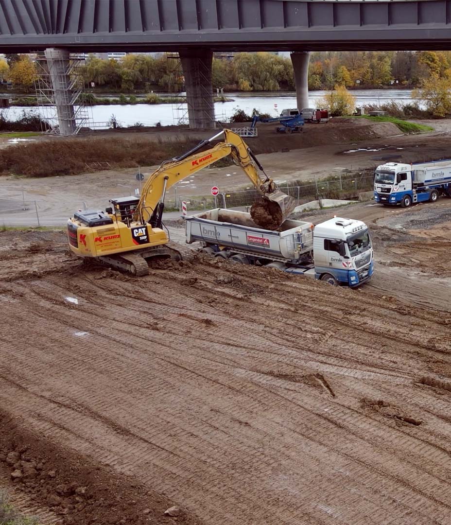 Ein Bagger belädt einen LKW mit Erde auf einer Baustelle an der Autobahn A6